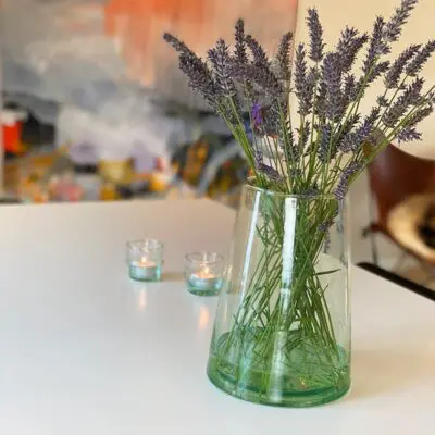Marokkanische mundgeblasene Vase mit Blumen darin und Teelichthaltern dahinter