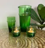 grüner marokkanischer mundgeblasener Beldi-Krug ohne Henkel neben anderen grünen Glasartikeln