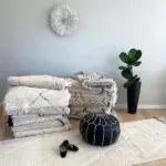 Moroccan handmade pouf in black with white pattern, next to beni ouarain rug