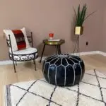 Moroccan handmade pouf in black with white pattern, on top of beni ouarain carpet and other products