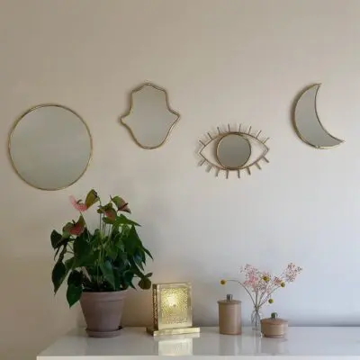 Different mirrors with gold trim hanging on the wall next to each other