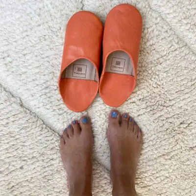 Moroccan handmade slippers in orange with foot model on the side