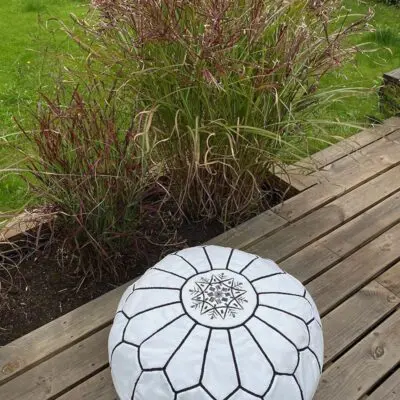 Moroccan handmade pouf in white with black pattern, standing outside on a pavilion