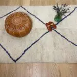 Marokkaanse leren poef met wit borduurwerk op beni ouarain tapijt