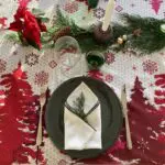 Serviette en tissu marocain brodée à la main avec bordure verte sur une assiette sur une table dressée avec des décorations de Noël