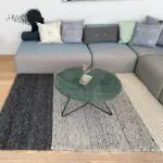 Moroccan handwoven carpet in shades of gray and beige with wool details, lying under a coffee table in a living room