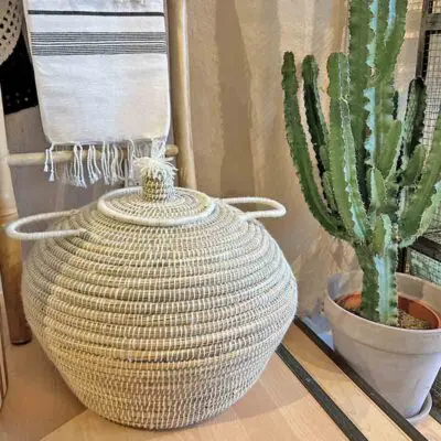 Large Moroccan handmade basket in natural rattan with white threads, standing in residence