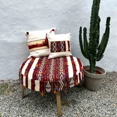 Grote handgemaakte boho poef met Marokkaans design met kussens erop en cactus ernaast