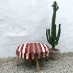 Großer handgefertigter Boho-Pouf mit marokkanischem Design neben Kaktus