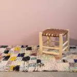 Marokkanischer handgewebter Boucherouite-Teppich mit mehrfarbigem Muster, mit Hocker darauf