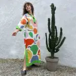 Model in Moroccan handwoven dress in multicolored fruit pattern next to cactus