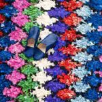 Handvävd boucherouite matta i flerfärgat diamantmönster, med midnattsblå tofflor ovanpå, nära