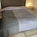 Moroccan handwoven bedspread with gray square pattern, lying on a made bed