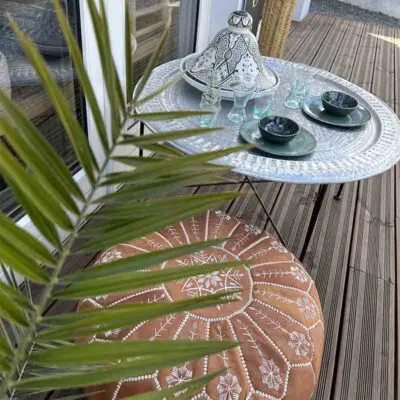 Table de plateau faite à la main avec un motif marocain debout à l'extérieur avec de la vaisselle et un plat à mandarine sur le dessus