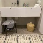 Moroccan handwoven hammam towel in blue with white Moroccan pattern lying on a stool in a bathroom
