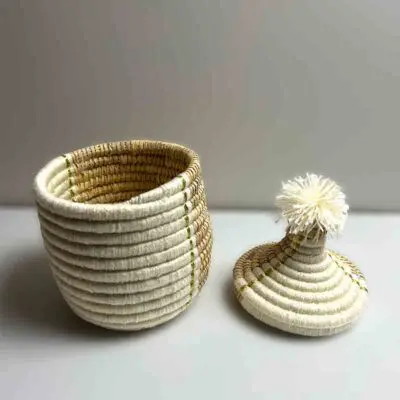 Small Moroccan handmade basket in natural rattan and white with tassel on top of the lid, the lid is removed
