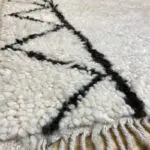 Tapis marocain blanc en laine Beni Ouarain avec motif pyramidal en noir sur les côtés, fermer