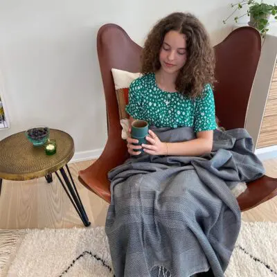 Modell sitzt auf einem Stuhl und hält einen marokkanischen handgefertigten Beldi-Becher in Grün in der Hand
