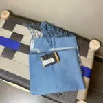 Moroccan handwoven hammam towel in blue with a bar of soap on top, on top of a bench