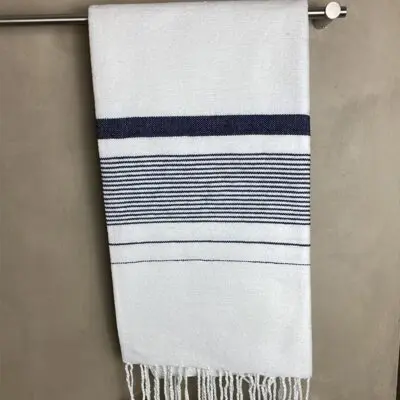 white Moroccan handmade hammam towel with black stripes, hanging in a bathroom