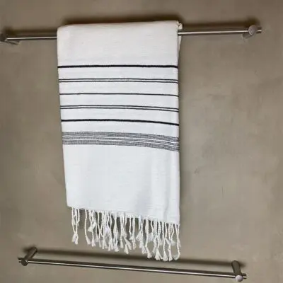Hivdt marokkansk håndlavet hammam håndklæde med sorte striber, hængende på et badeværelse