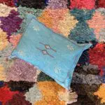 Moroccan handwoven cactus silk cushion cover in turquoise on boucherouite rug