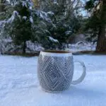 Moroccan handmade ceramic mug with handle in ethnic chic pattern, standing outside in snow