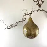 Marockansk handgjord rund lampa av guld, hängande på en gren