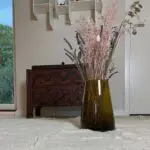 Moroccan hand-blown vase in brown with flowers on top of a white carpet