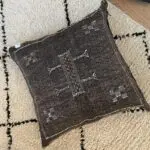 Moroccan handwoven cushion cover of cactus silk in dark brown color with white details on beni ouarain rug