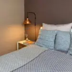 Marokkanische handgewebte Tagesdecke mit grauem Quadratmuster, die auf einem gemachten Bett liegt