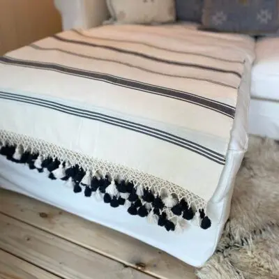Marokkansk håndvævet plaid i hvid med sorte striber, liggende på en sofa
