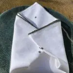 Serviette en tissu marocaine brodée à la main avec bordure verte sur une assiette, gros plan