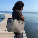 Model hält marokkanische handgewebte Tasche in Brauntönen auf einer Brücke