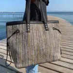 Model holding Moroccan handwoven bag in shades of brown out on a bridge