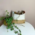 Trousse de toilette marocaine tissée à la main en gris et beige avec des articles de toilette à côté d'une plante