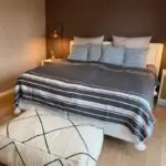 Marokkanische Tagesdecke aus Gras mit weißen Pompons auf einem Bett