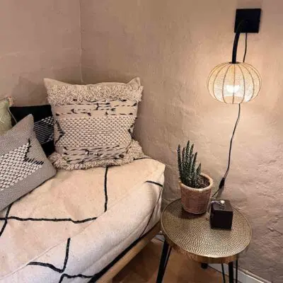 Round Moroccan handmade wall lamp in braided raffia, hanging as a reading lamp in a cozy corner