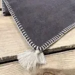 Charcoal gray Moroccan hand-embroidered placemats with white border and white pompoms, close