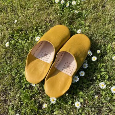 Moroccan handmade slippers in yellow on grass, back view