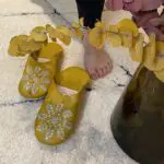 Babouches marocaines artisanales jaune moutarde à paillettes sur tapis Beni Ouarain avec bouffantes sur le côté, fermer