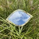 Marokkaanse handgemaakte ooglidvormige spiegel met gouden rand, liggend in het gras