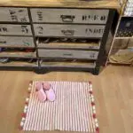 Moroccan handwoven bath mat in white with pink stripes, with Moroccan slippers on top, next to bookcase