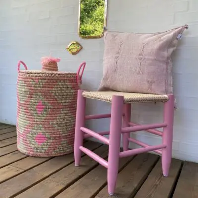 Moroccan handmade stool in pink, with pink cushion cover and pink basket next to it