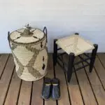 Handwoven basket with Moroccan pattern in black, next to black stool and black slippers