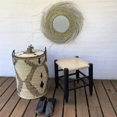 Moroccan handmade stool in black with cannage rattan seat, next to basket with black pattern and black slippers
