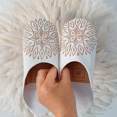 Model holding Moroccan handmade slippers in white with pattern