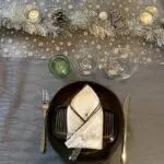 Serviette en tissu marocain brodée à la main avec bordure marron sur une assiette sur une table dressée avec des décorations de Noël