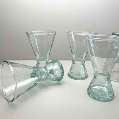 Handgefertigte transparente Beldi-Weingläser, eines davon auf einem Tisch liegend