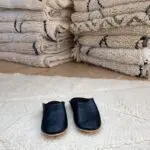 Moroccan handmade slippers in black on top of beni ouarain rug